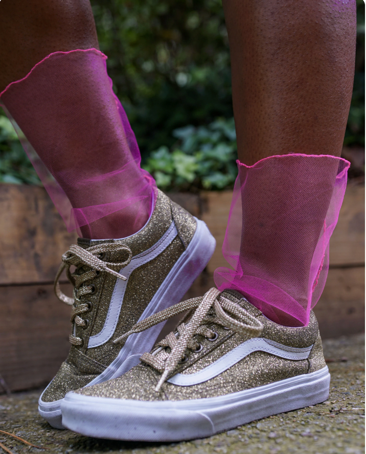 Glittery sneakers with pink sheer socks worn outdoors.